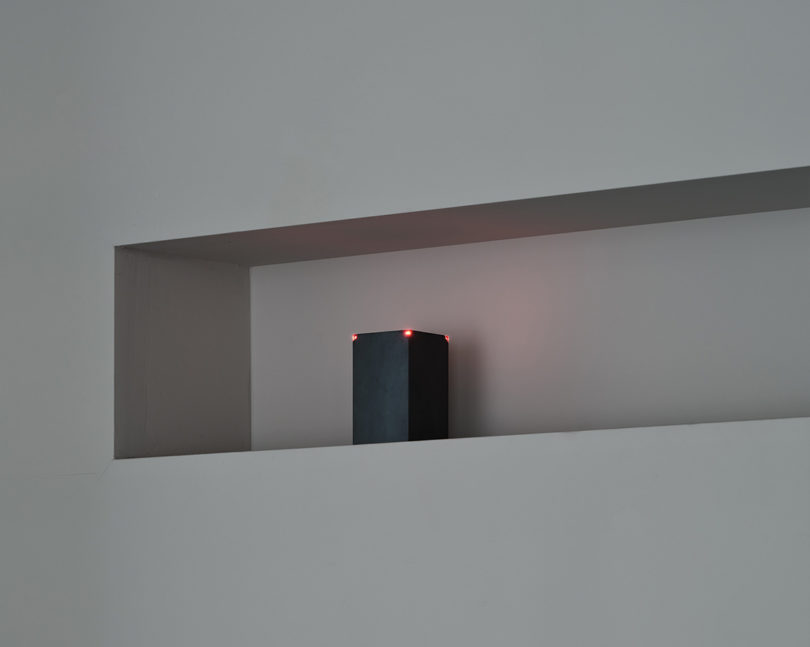 angled view of embedded shelf holding a black block light fixture with small red lights at corners