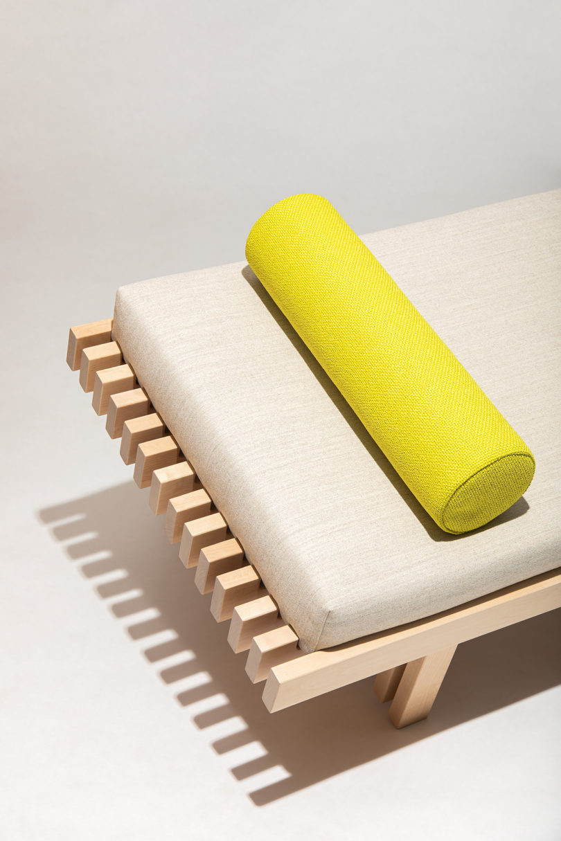 light wood daybed with light upholstery and neon yellow bolster pillow