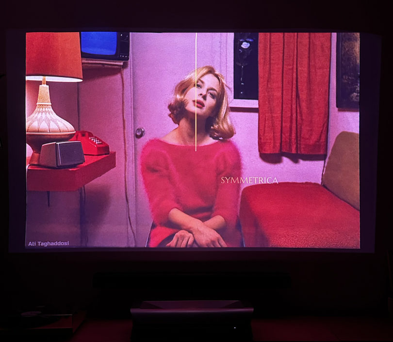 A projection set showing Nastassja Kinski seated wearing a red-pink sweater, a still from the movie, "Paris, Texas"