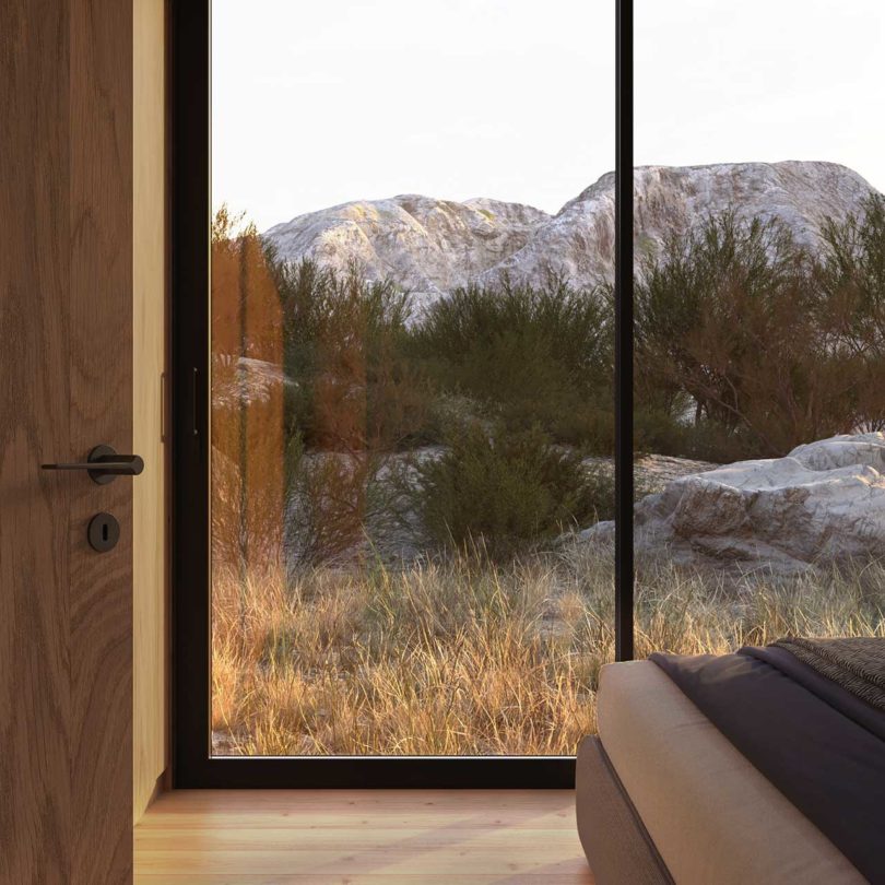 نمای انتهایی اتاق خواب مدرن که از پنجره شیشه ای رو به کوه است
