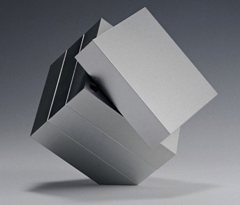 sculptural aluminum four-piece grinder standing on a corner with top section rotated