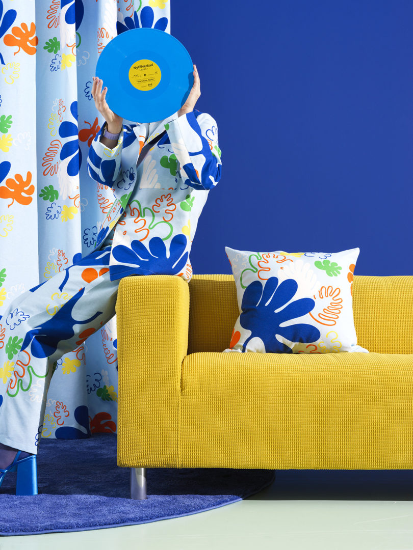 کاناپه زرد در برابر دیوارهای آبی روشن با فردی با لباس خواب که یک رکورد آبی روی صورت خود دارد.