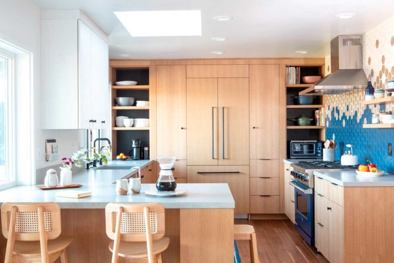 آشپزخانه مدرن بازسازی شده با کابینت های چوبی سبک و کاشی های شش ضلعی موزاییکی روی دیوارها