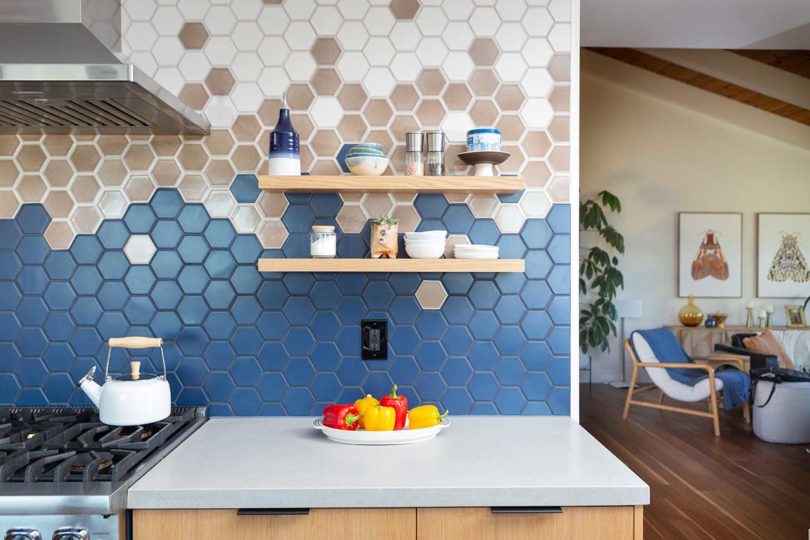 آشپزخانه مدرن بازسازی شده با کابینت های چوبی سبک و کاشی های شش ضلعی موزاییکی روی دیوارها