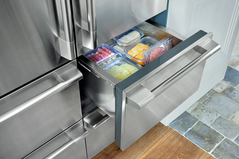 open stainless drawer inside of a french door refrigerator/freezer filled with food
