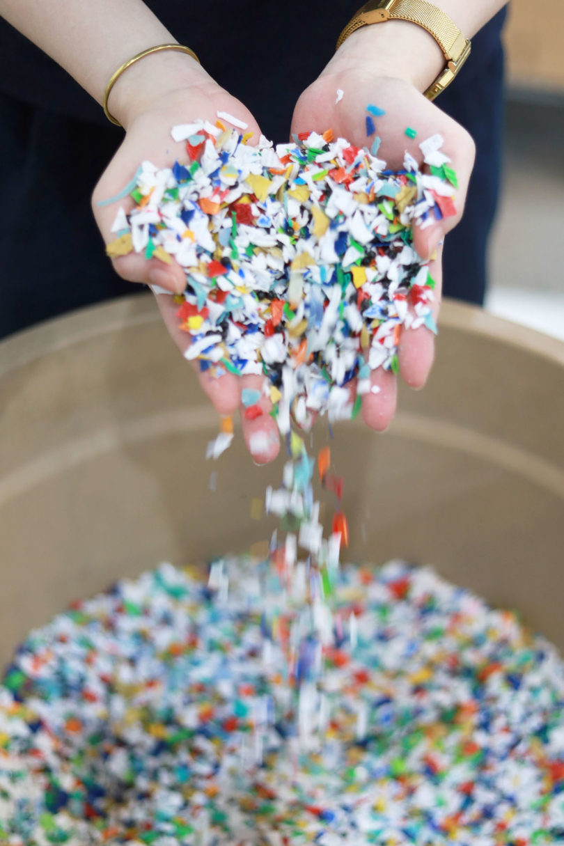 multicolored plastic scraps pouring out of someone's hands into a container