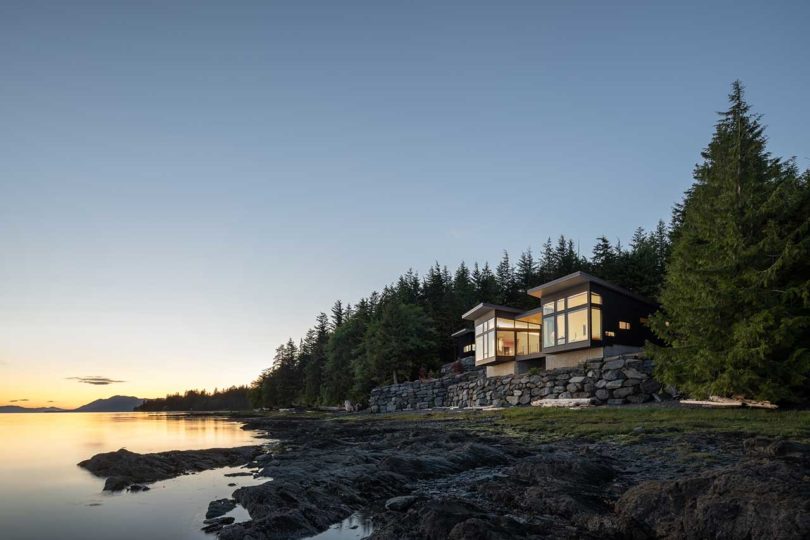 exterior evening view of modern house atop stacked rocks above water