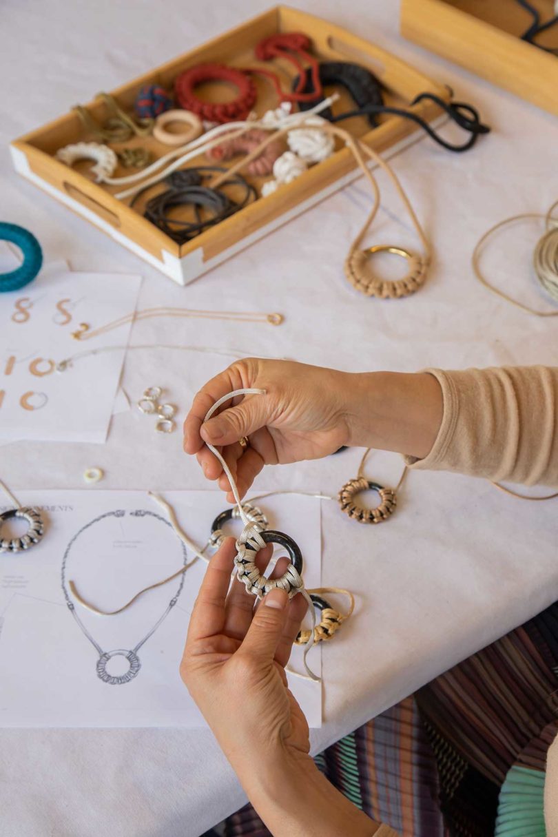 view down onto a work table with two sets of hands making jewelry