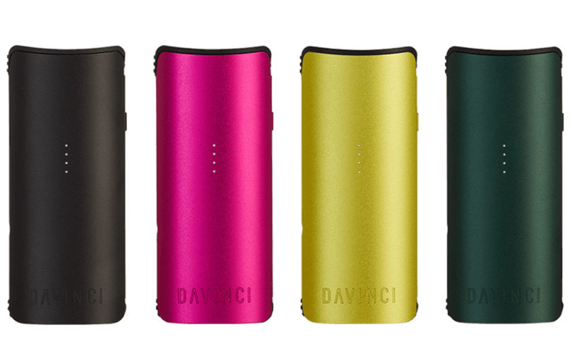 Four DaVinci vaporizers in black, magenta, yellow and dark green matte metallic finishes floating against white background.