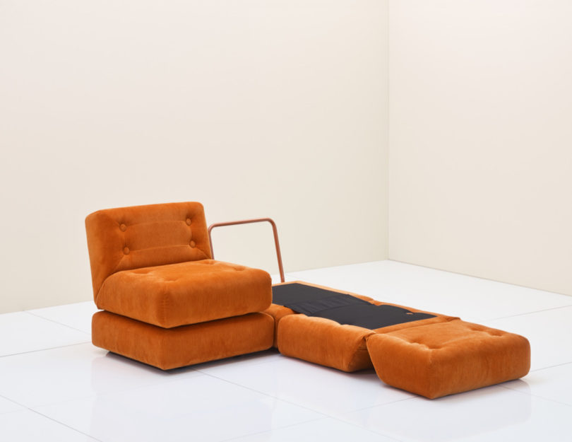 two orange chairs, one folded out into a bed