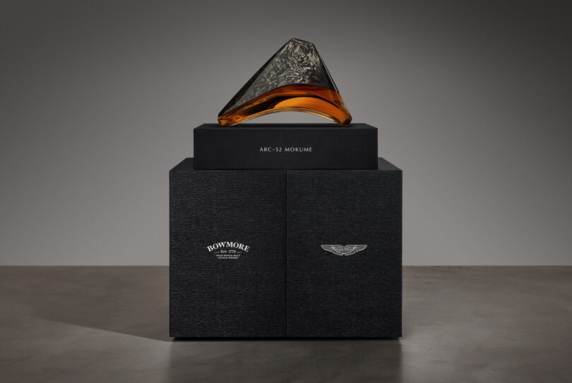 All black box packaging with Bowmore decanter made of glass and carbon fiber in an arc-like form set on top.