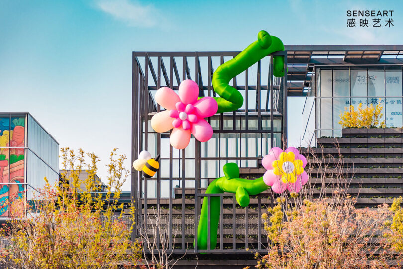 outdoor installation of two large pink flowers and a bee