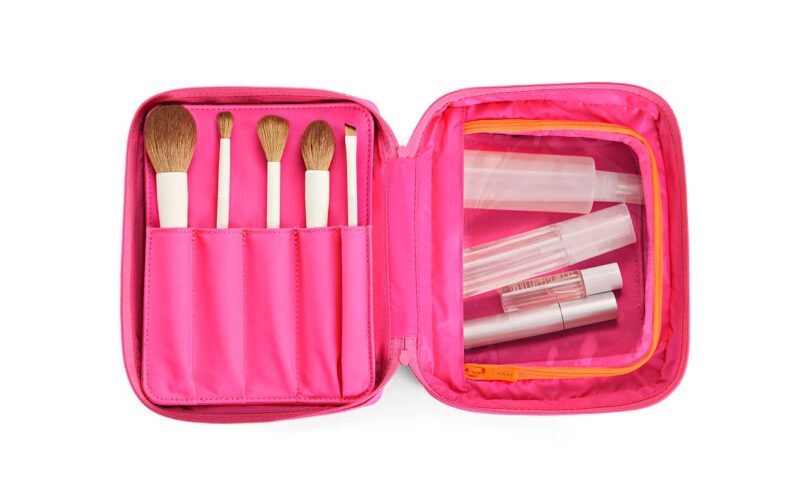 looking down into neon pink cosmetics case with brushes and bottles