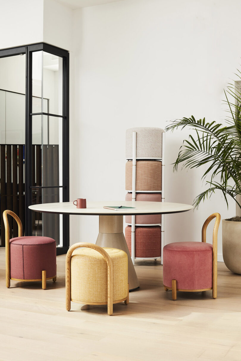 three warm toned pouf stools arranged around around a round table and four more stacked in the background