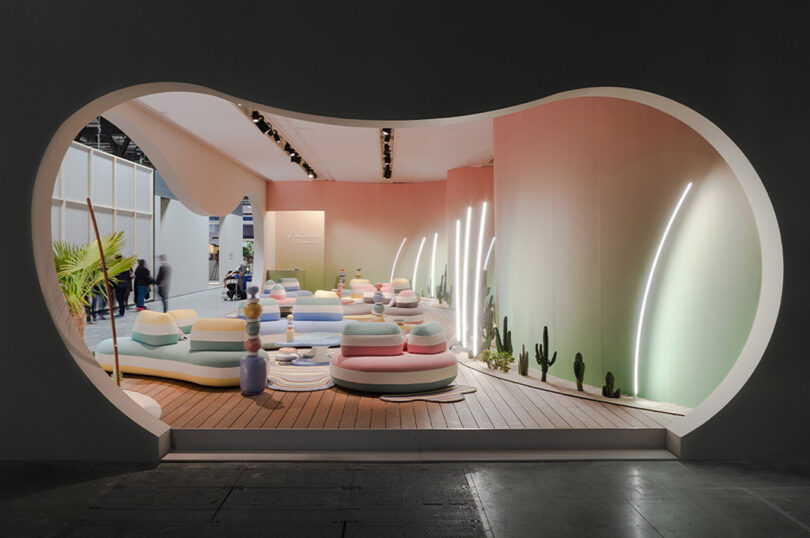 looking into a showroom displaying pastel colored organically shaped pouf seating, tables, and rugs