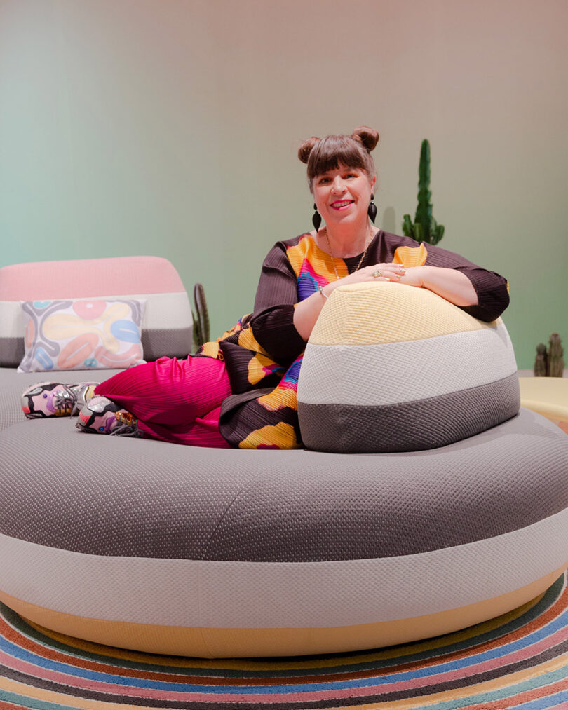 light-skinned woman with dark hair in space buns reclines on a large pouf