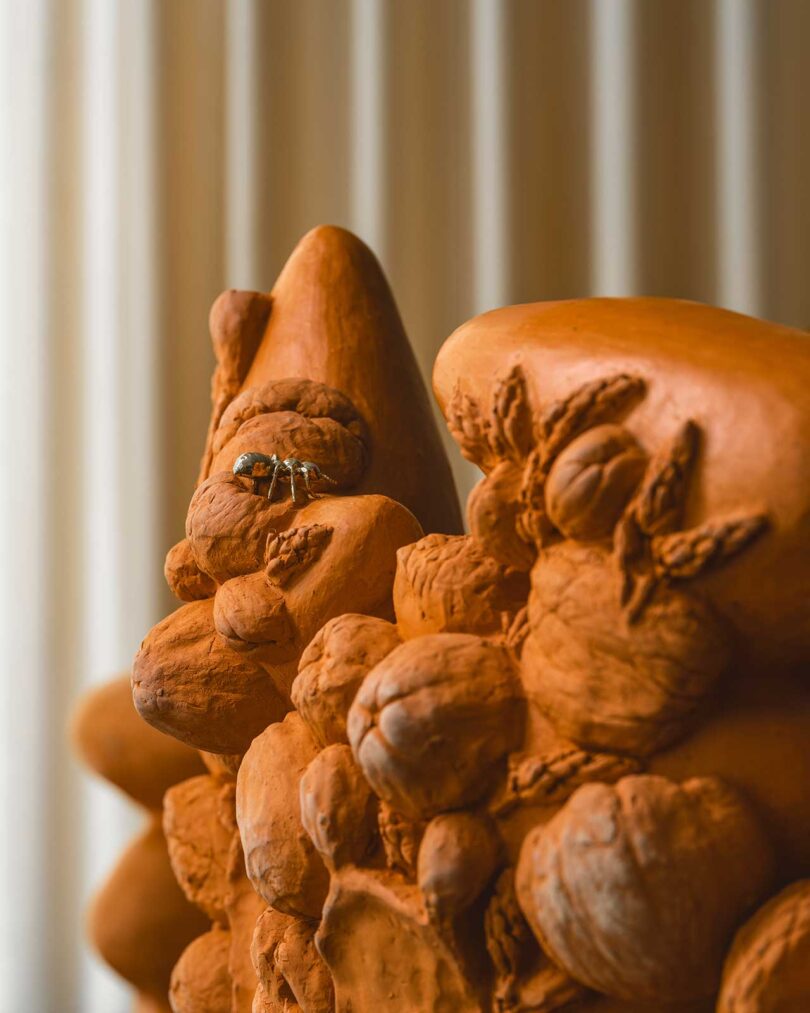 closeup view of terracotta floral chair sculpture with brass bug