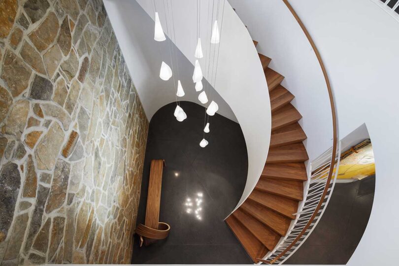 down interior view of modern circular staircase with wood treads and white banisters