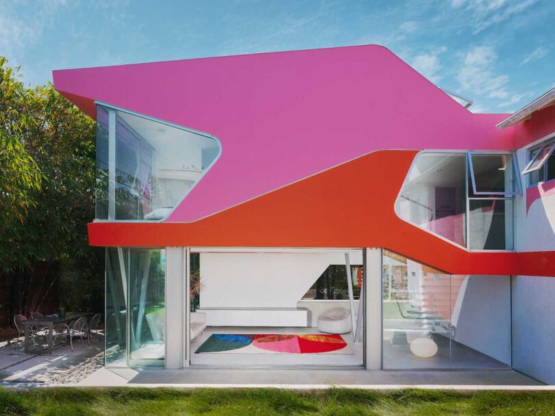 exterior view of ultra modern house with pink and red roof with view of colorful rug inside