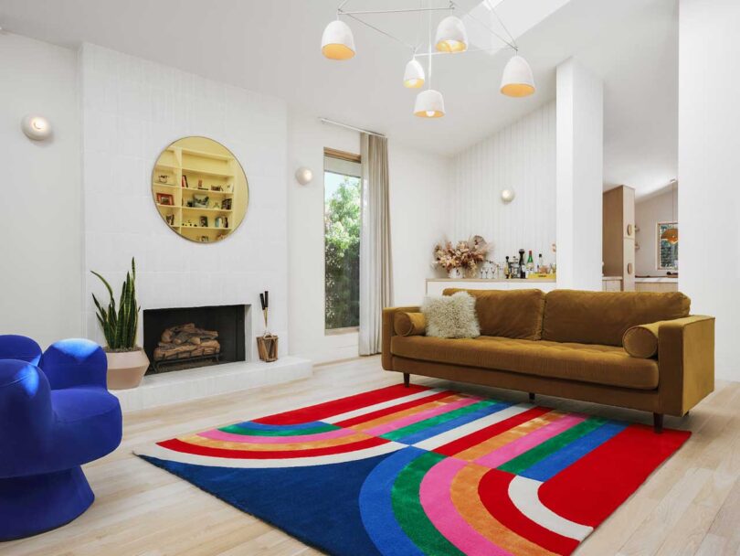 angled interior view of modern living room with white walls, gold sofa, and graphic colorful rug