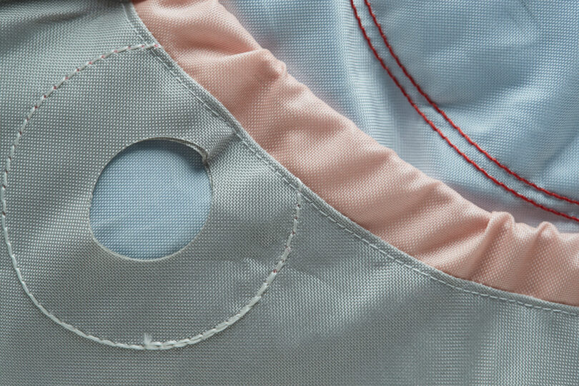 Detail of round pastel blue colored pillow made from recycled car air bags with peach detailing.