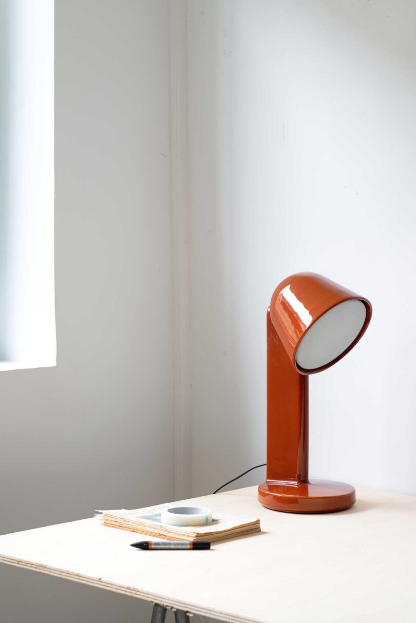 Angled view of single ceramic lamp on table in rust color