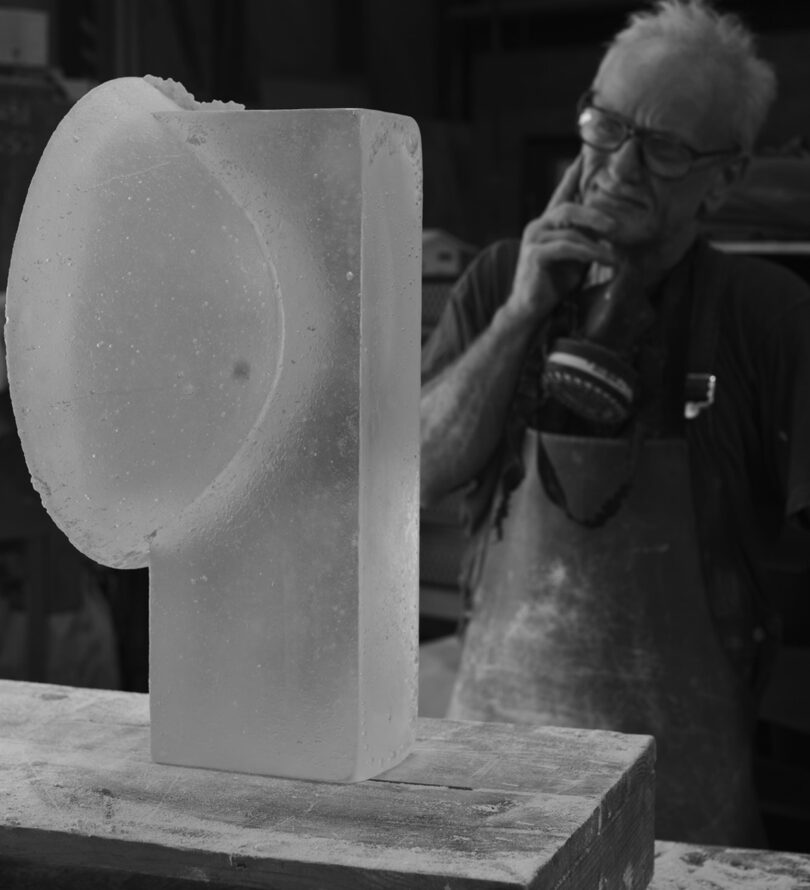 Glass artist Peter Kovacsy thoughtfully reviewing an unpolished Vestige light sculpture upon removing it from its mold