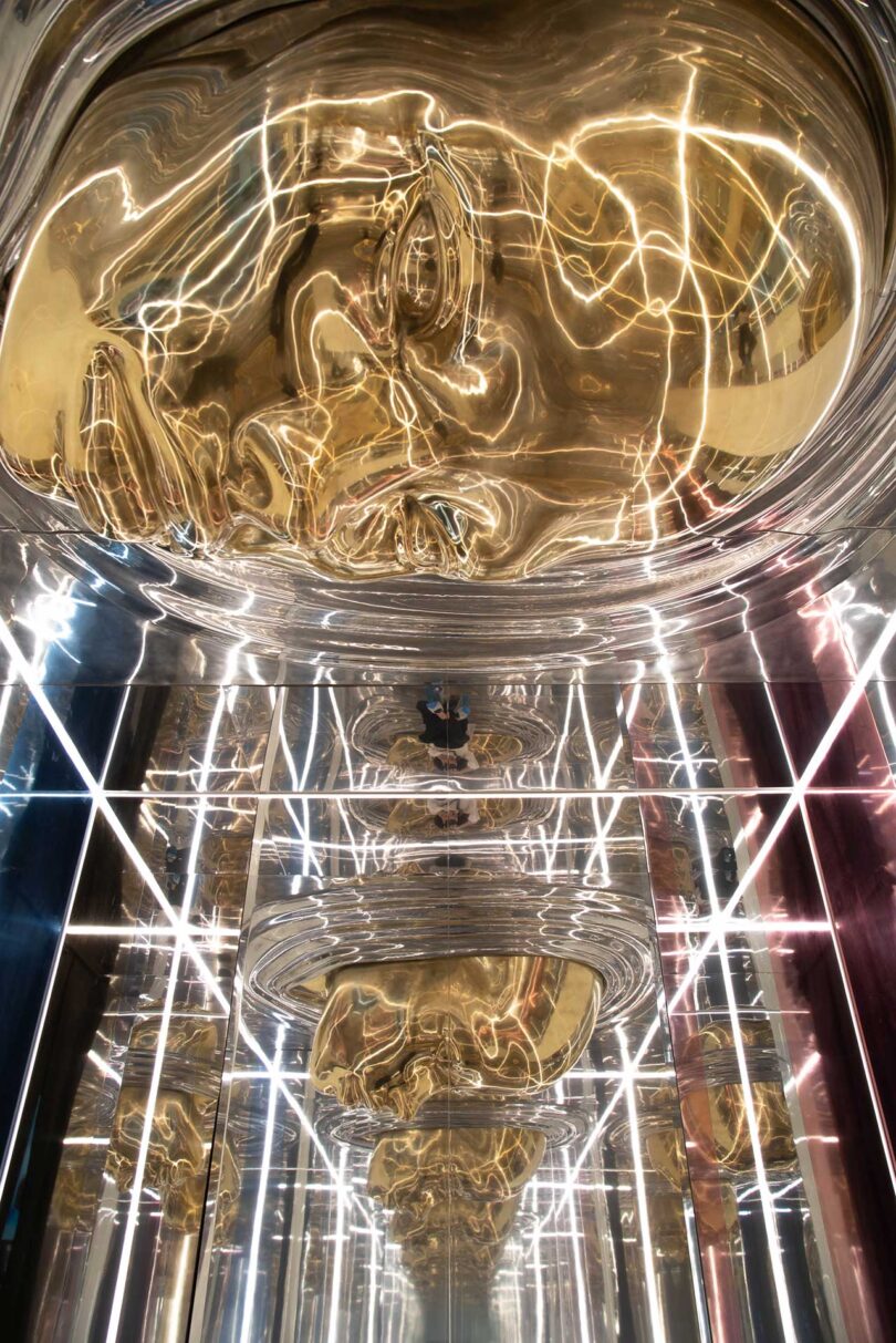 up view of mirrored installation with gold faces and linear lights in white