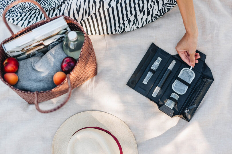 light-skinned hands interacting with diabetes tools in a black bag on a picnic blanket