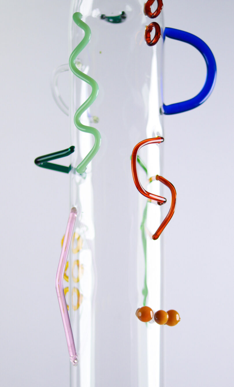 detail of a clear glass cylinder with abstract colored shapes of glass attached to the exterior