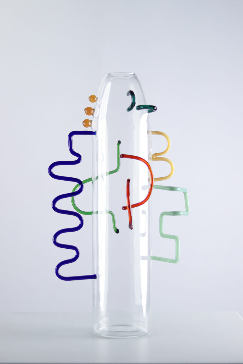 clear glass cylinder with abstract colored shapes of glass attached to the exterior