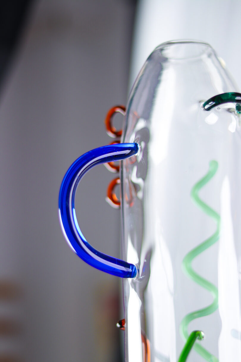 detail of a clear glass cylinder with abstract colored shapes of glass attached to the exterior