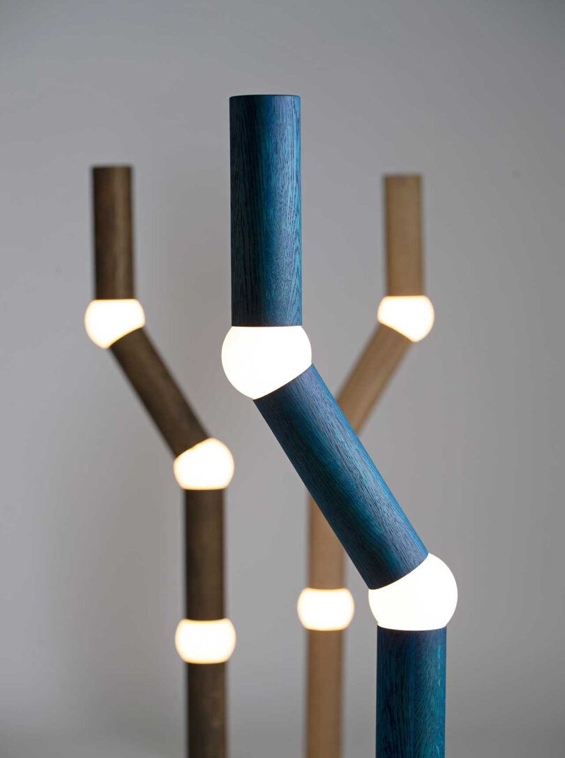 three long, slender floor lamps with four segments, each connected by a round lightbulb