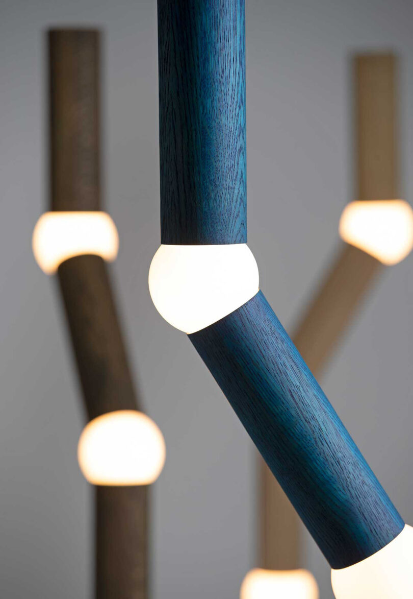 detail of three long, slender floor lamps with four segments, each connected by a round lightbulb