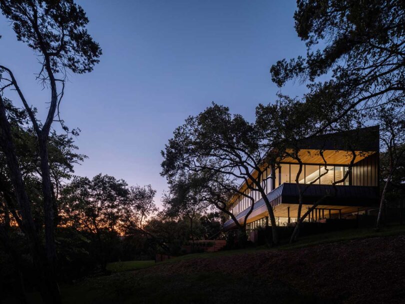 side exterior view of modern home with lights on at dusk