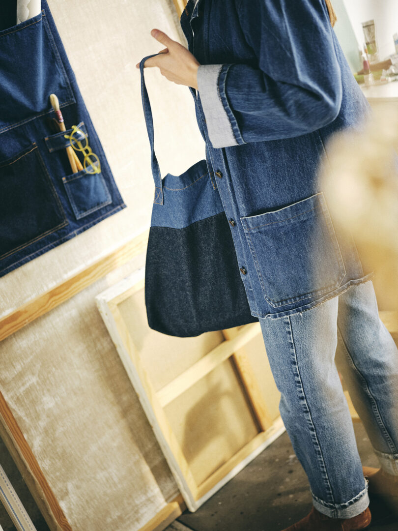 person wearing denim chore jacket and denim tote bag