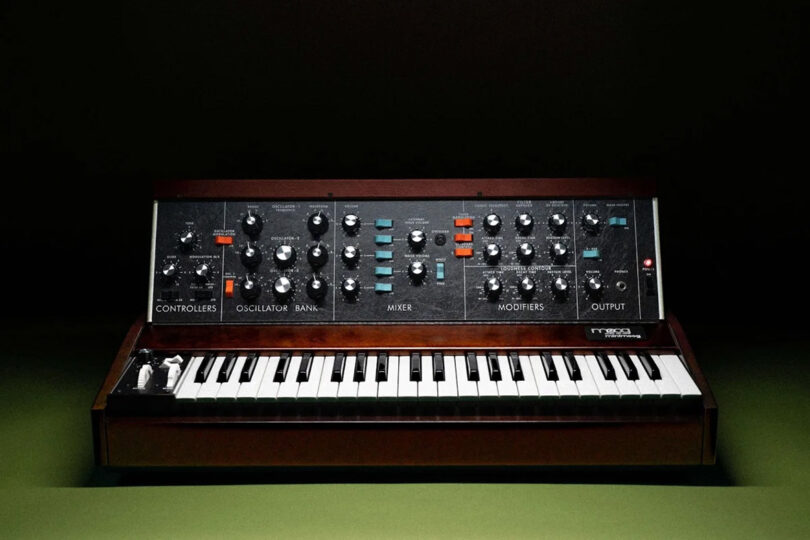 Moog Model D synthesizer in shadowed silhouette portrait set on green surface with all black shadowed background.