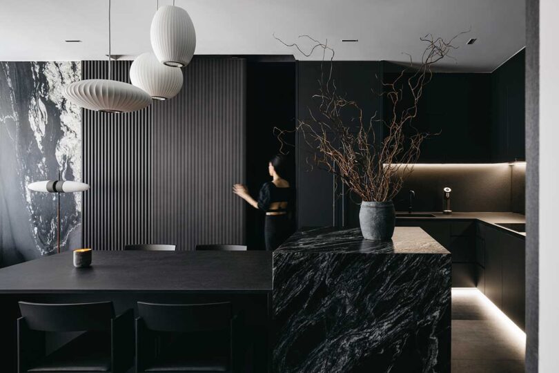 modern black kitchen with woman opening cabinet