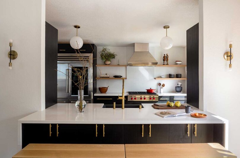 a modern contemporary kitchen with black cabinets and brass hardware
