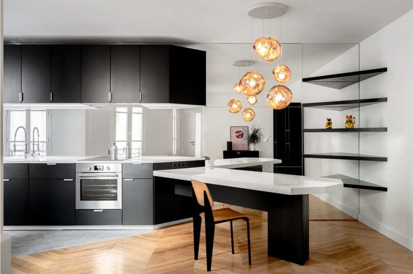 minimalist black and white kitchen with angled white island and mirror backsplash