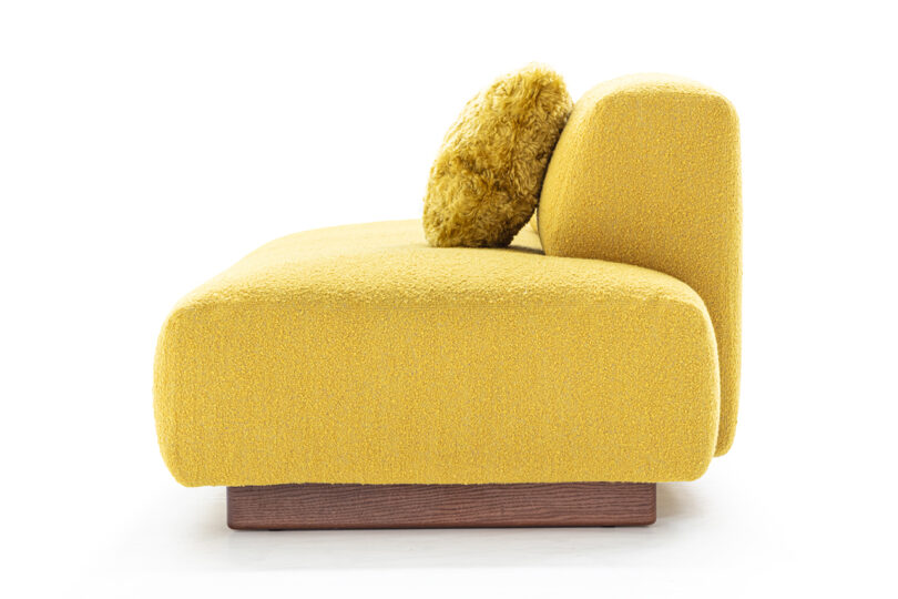 side of yellow armless sofa with pillows on white background