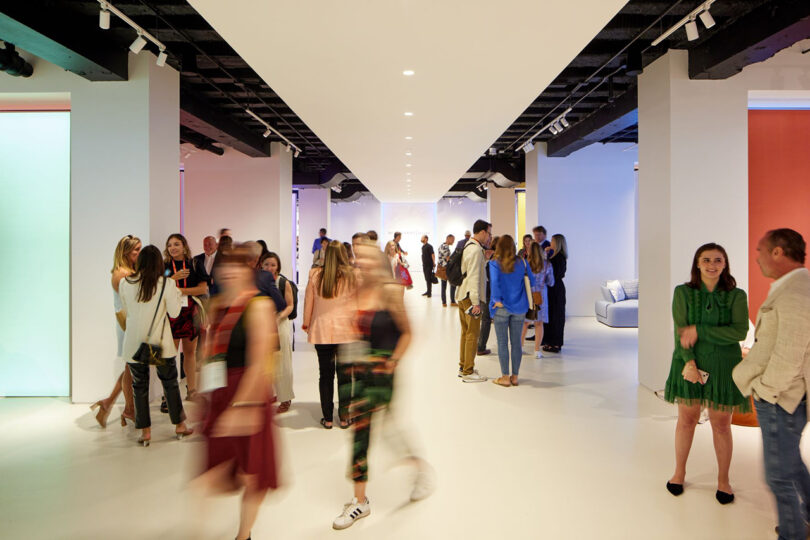 blurry crown of people walking through a white hallway