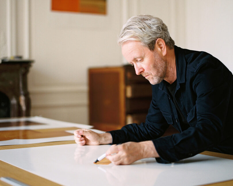 Ronan Bouroullec in his Parisian studio at his table sketching.