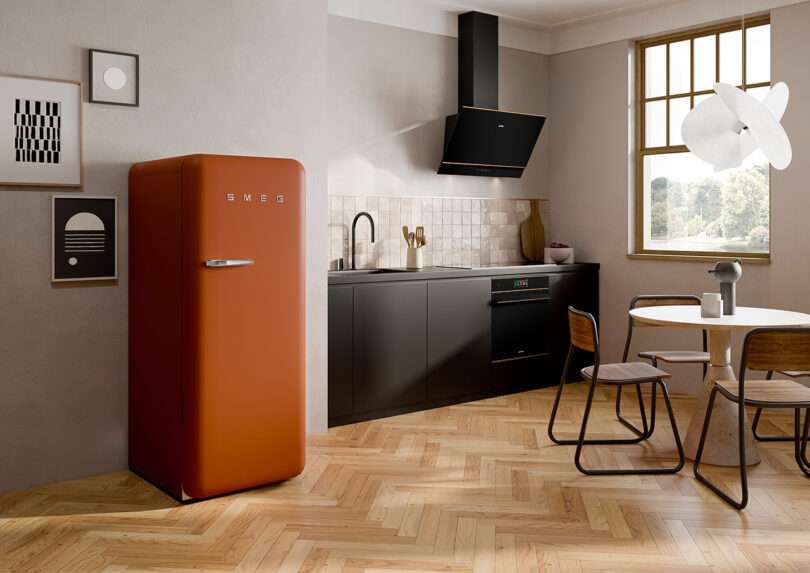 Smeg FAB28 Refrigerator in Rust in open kitchen with herringbone flooring.