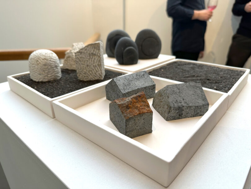 Small volcanic rock sculptures shaped like rocks in white square trays.