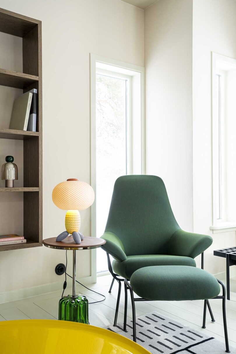 interior view of seating vignette of green chair with pedestal table and glass lamp