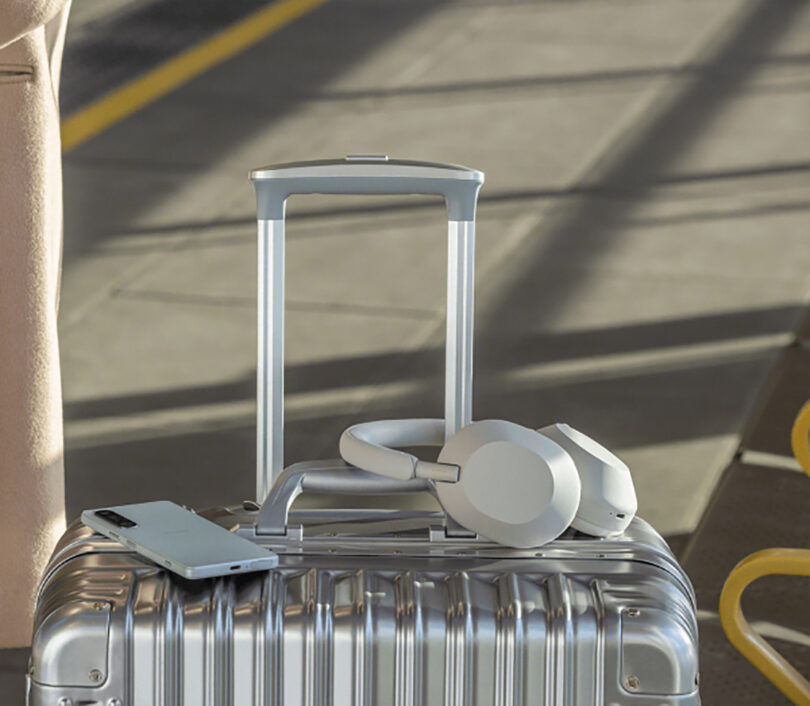 Aluminum suitcase with handles propped up with Sony smartphone and headphones set on top of it.