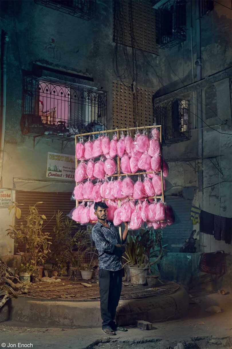 man standing on dilapidated street holding pink cotton candy