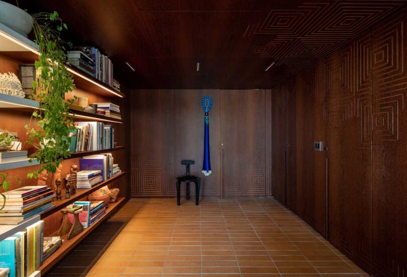 wood paneled dark hallway with view of entry door and lit book shelf on side