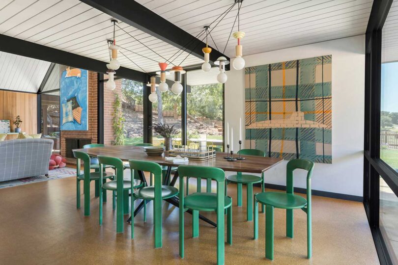 angled interior view of mid-century modern dining room with green chairs